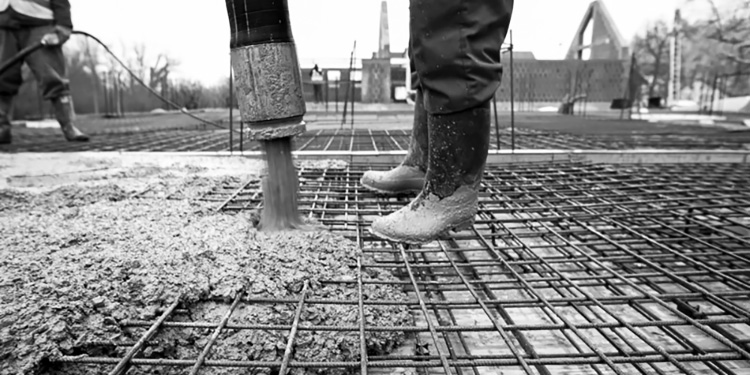 Concrete being poured over a grid of metal rebar.