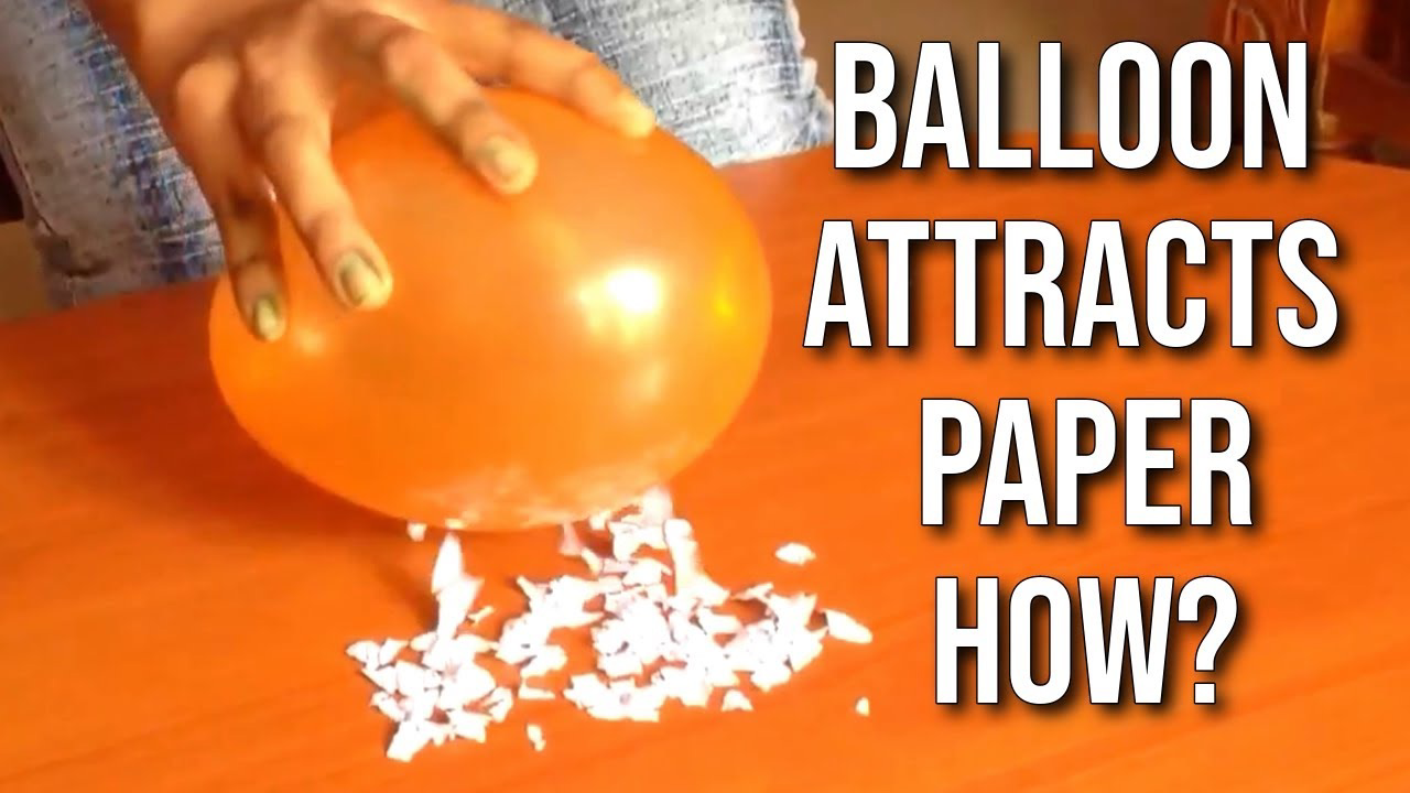 A hand holding an orange balloon attracting small pieces of paper on a table with the text 'Balloon attracts paper how?'