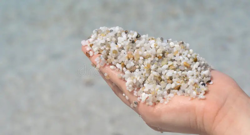 Hand holding quartz sand.