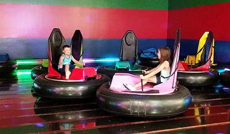 null Children riding bumper cars in an amusement center.
