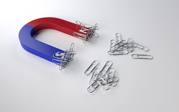 A horseshoe magnet attracting paper clips on a table.