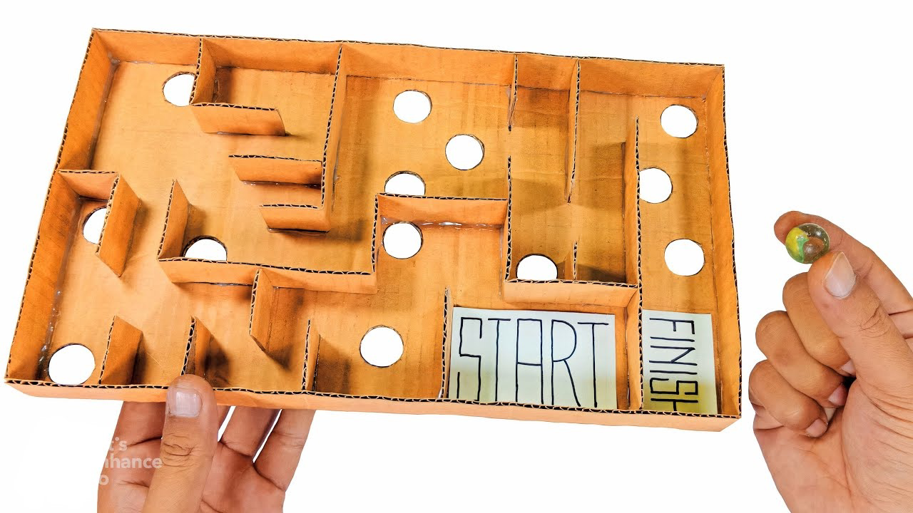 Cardboard maze game with start and finish areas and holes cut in the board.