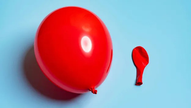 A red inflated balloon and a deflated red balloon on a blue background.