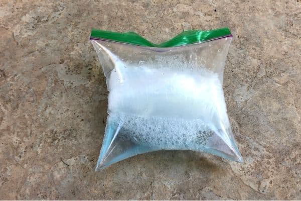 A zip-top bag containing baking soda and vinegar reacting to produce gas and bubbles.