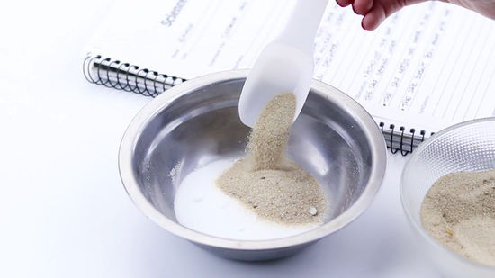 Sand being poured into a bowl containing salt