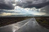 Carretera mojada bajo nubes oscuras.