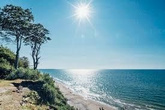 Paisaje de playa con cielo despejado y sol brillante.