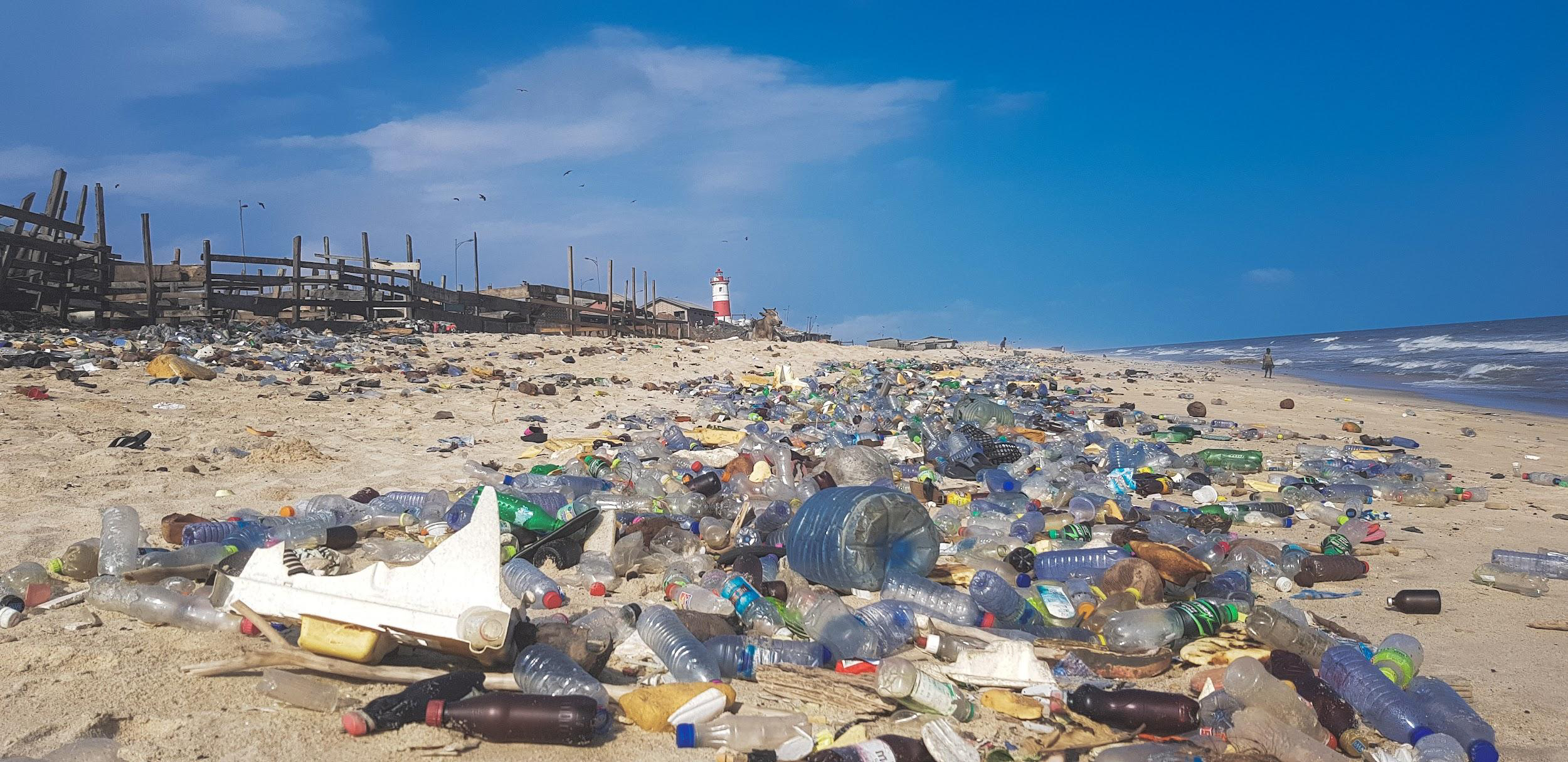 Pollution in the form of plastic bottles and rubbish scattered across a beach